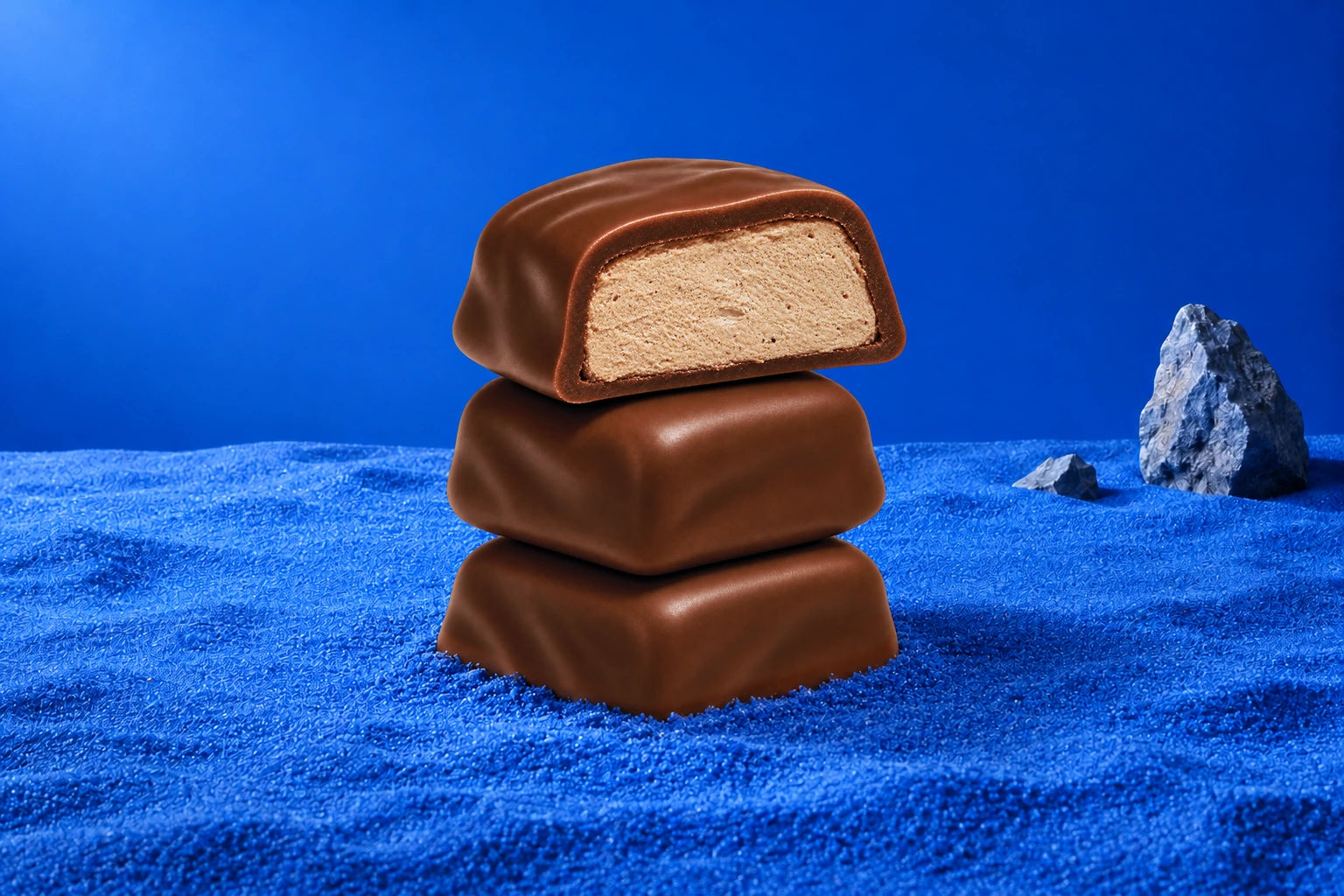 Stacked chocolate-covered Moon Magic bites on a blue background